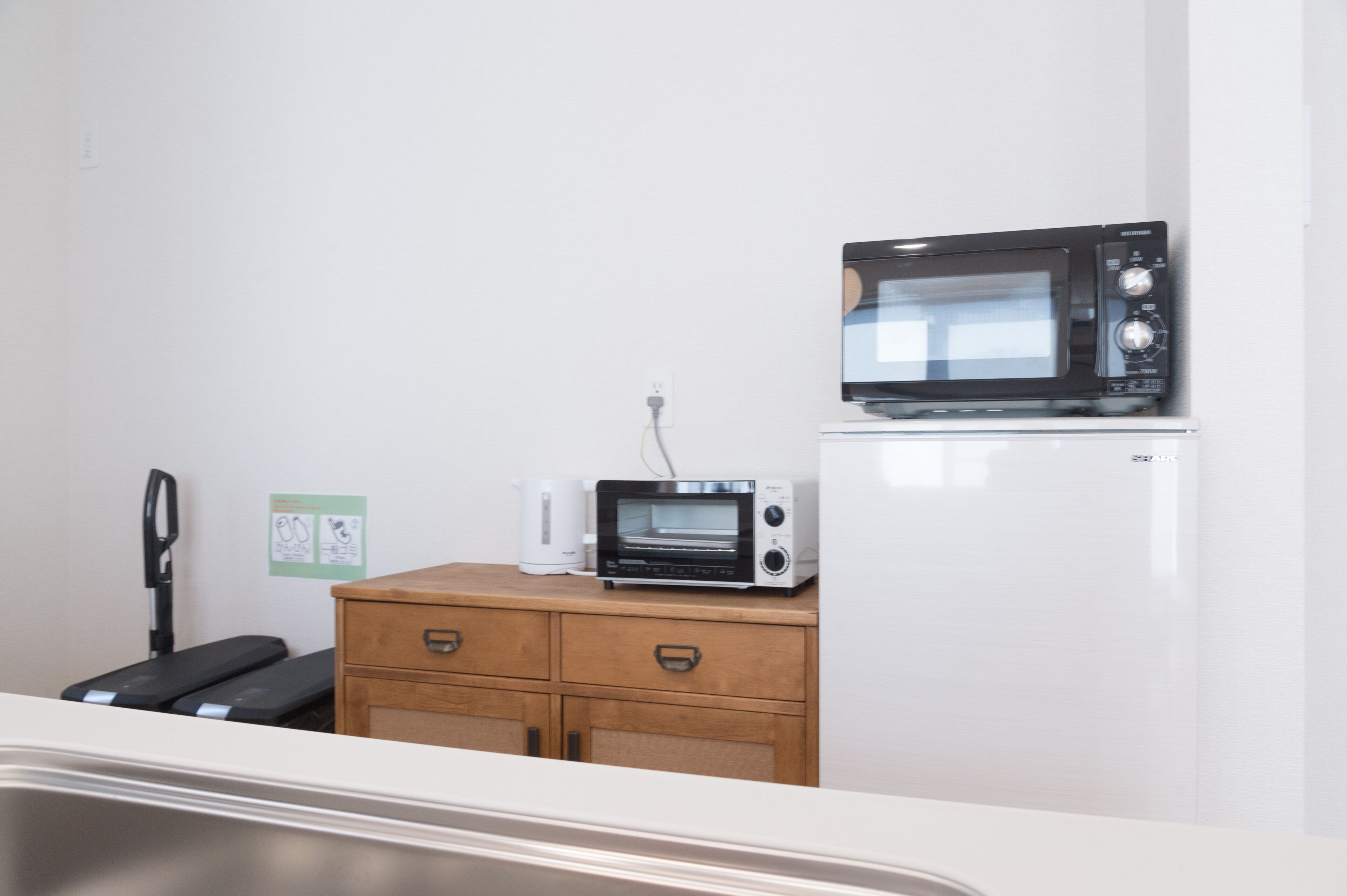 A kitchenette with a microwave, toaster oven, and a refrigerator.