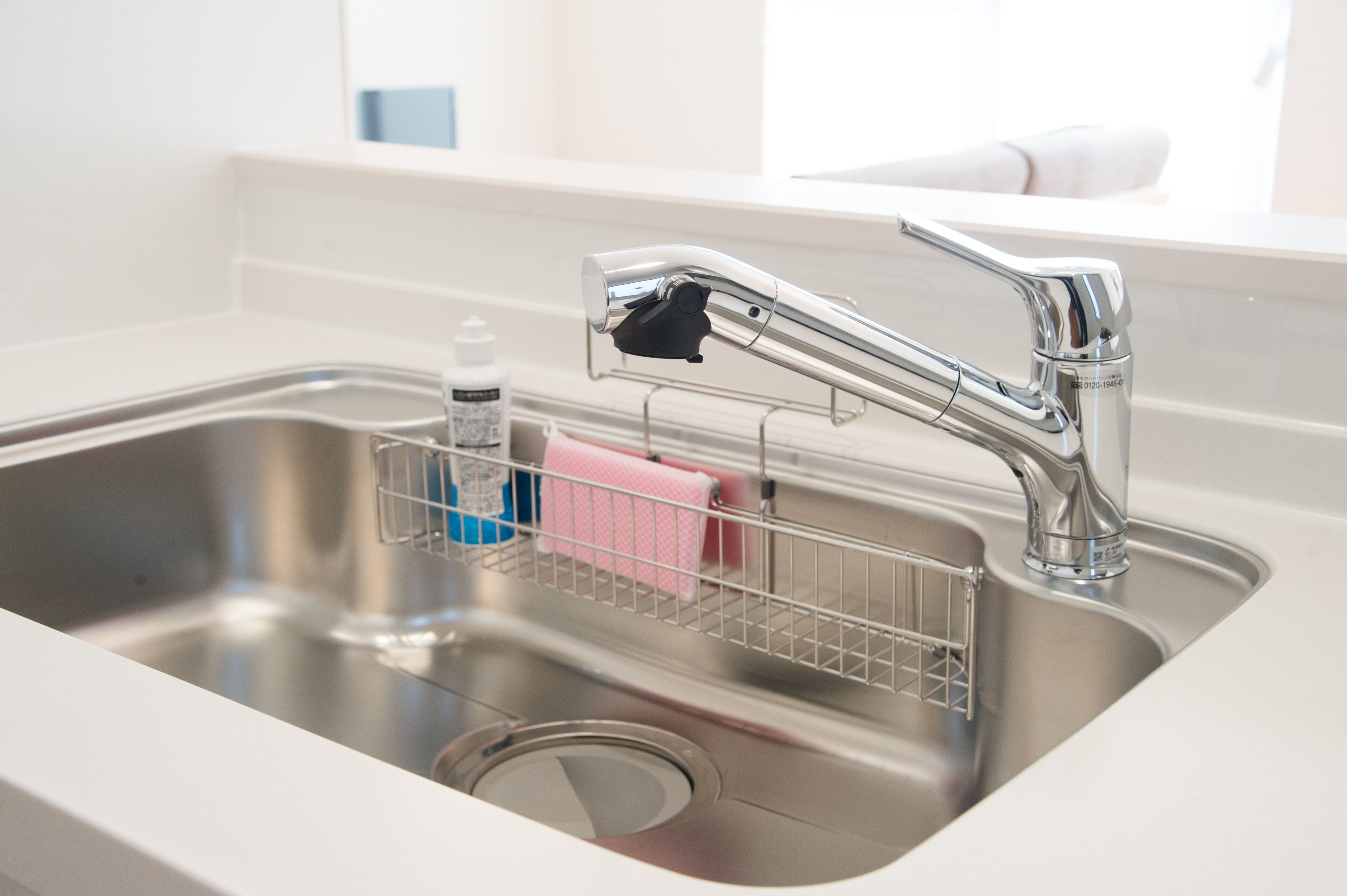 A stainless steel kitchen sink with a modern faucet, a soap dish, and a sponge rack.