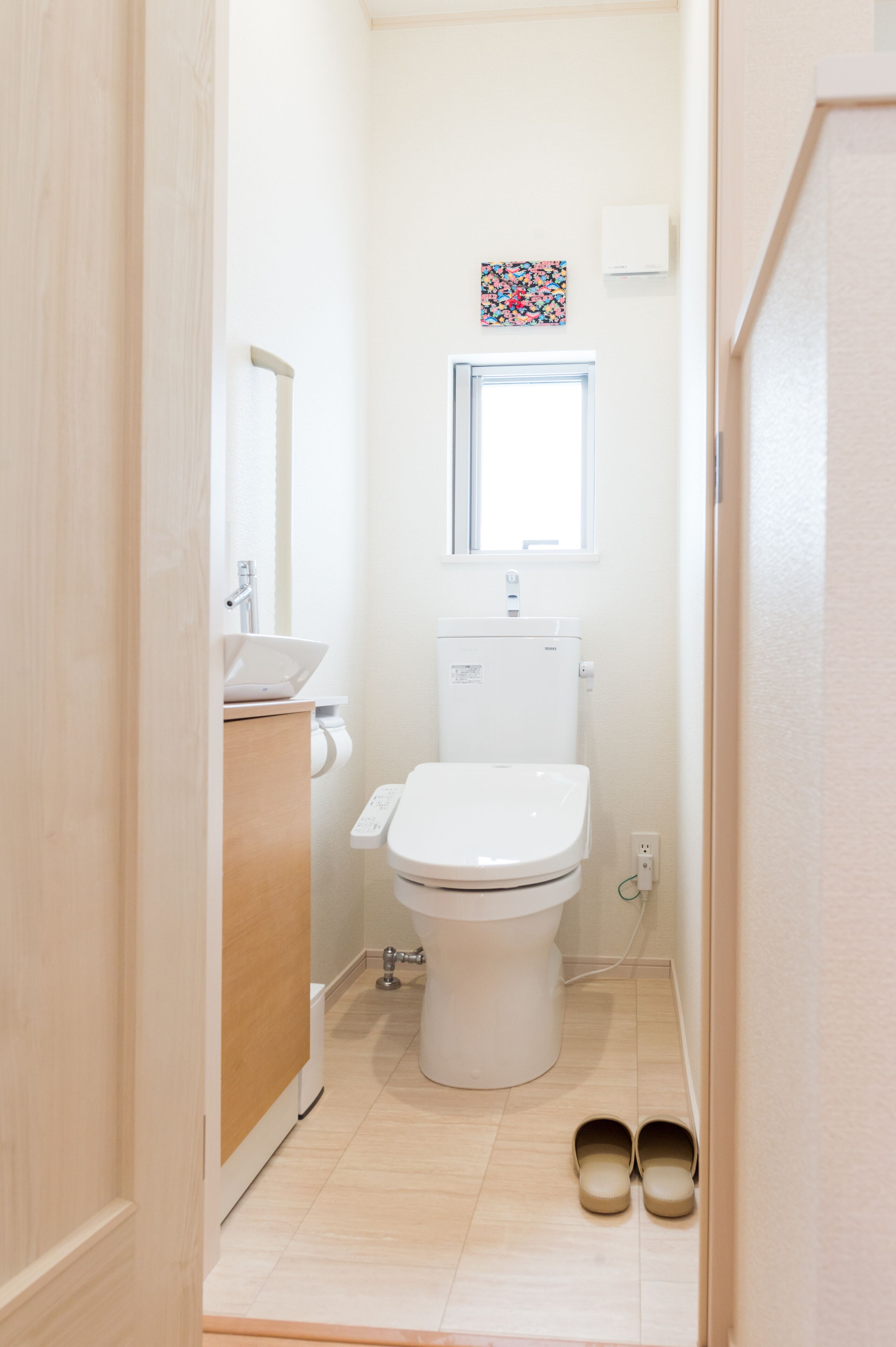 A small, clean bathroom with a toilet, sink, and a small window.