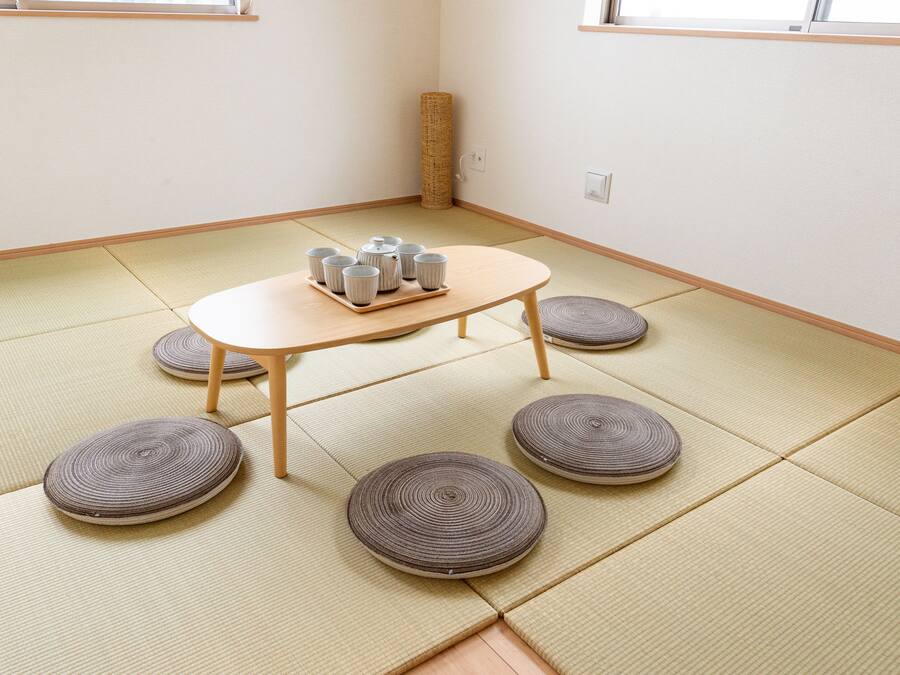A tatami mat room with a low table and cushions.
