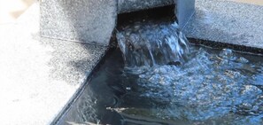 A water feature with water flowing from a stone structure into a basin.