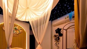 A room with a bed, a night sky ceiling, and a nightstand with a lamp. - Angel Hotel Nha Trang (Nha Trang)