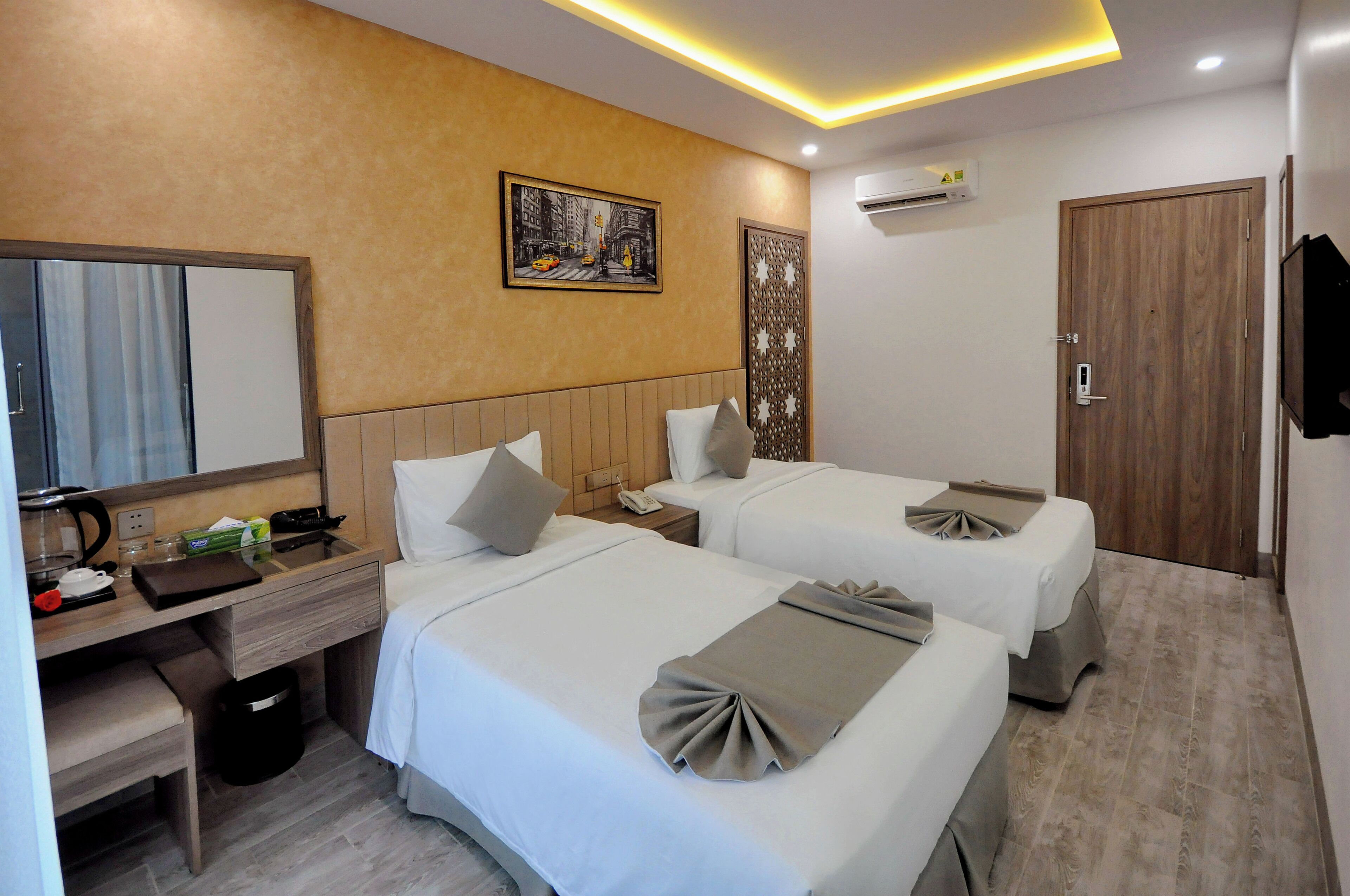 A hotel room with two beds, a desk with a telephone, a mirror, and a painting on the wall.