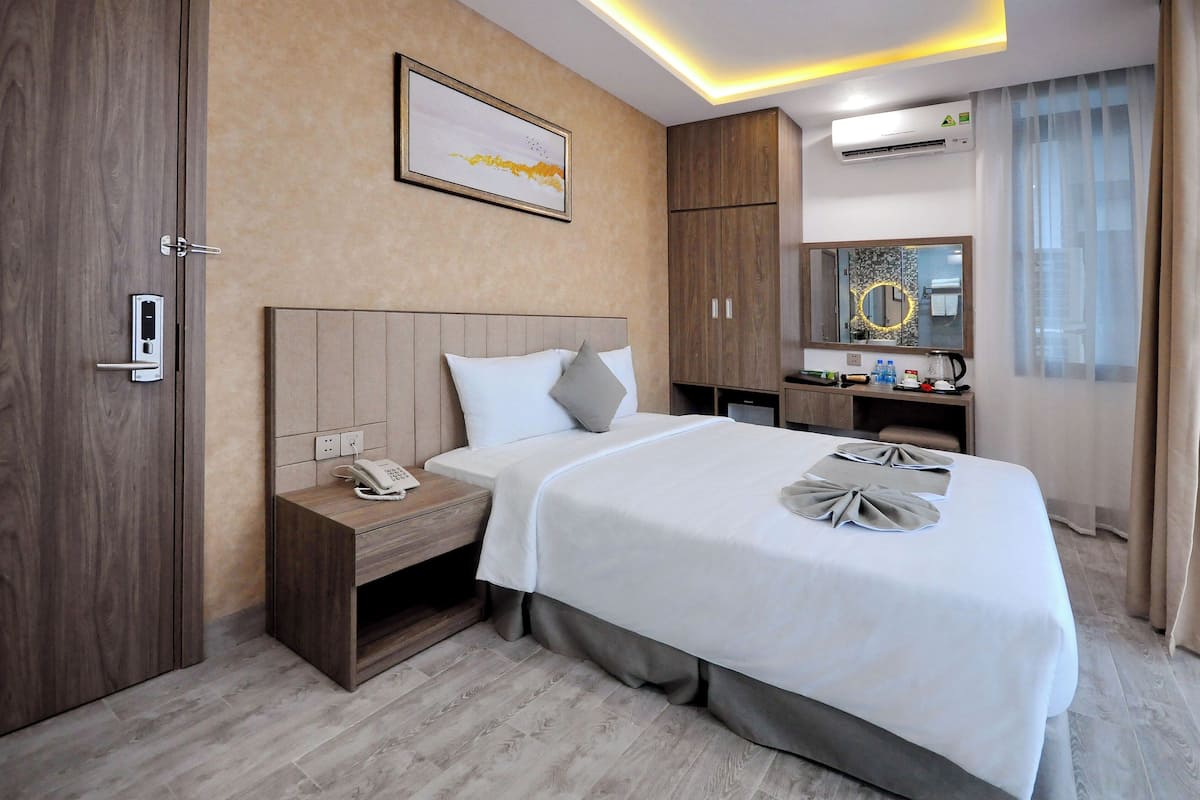A hotel room with a bed, bedside table, nightstand, and a mirror.