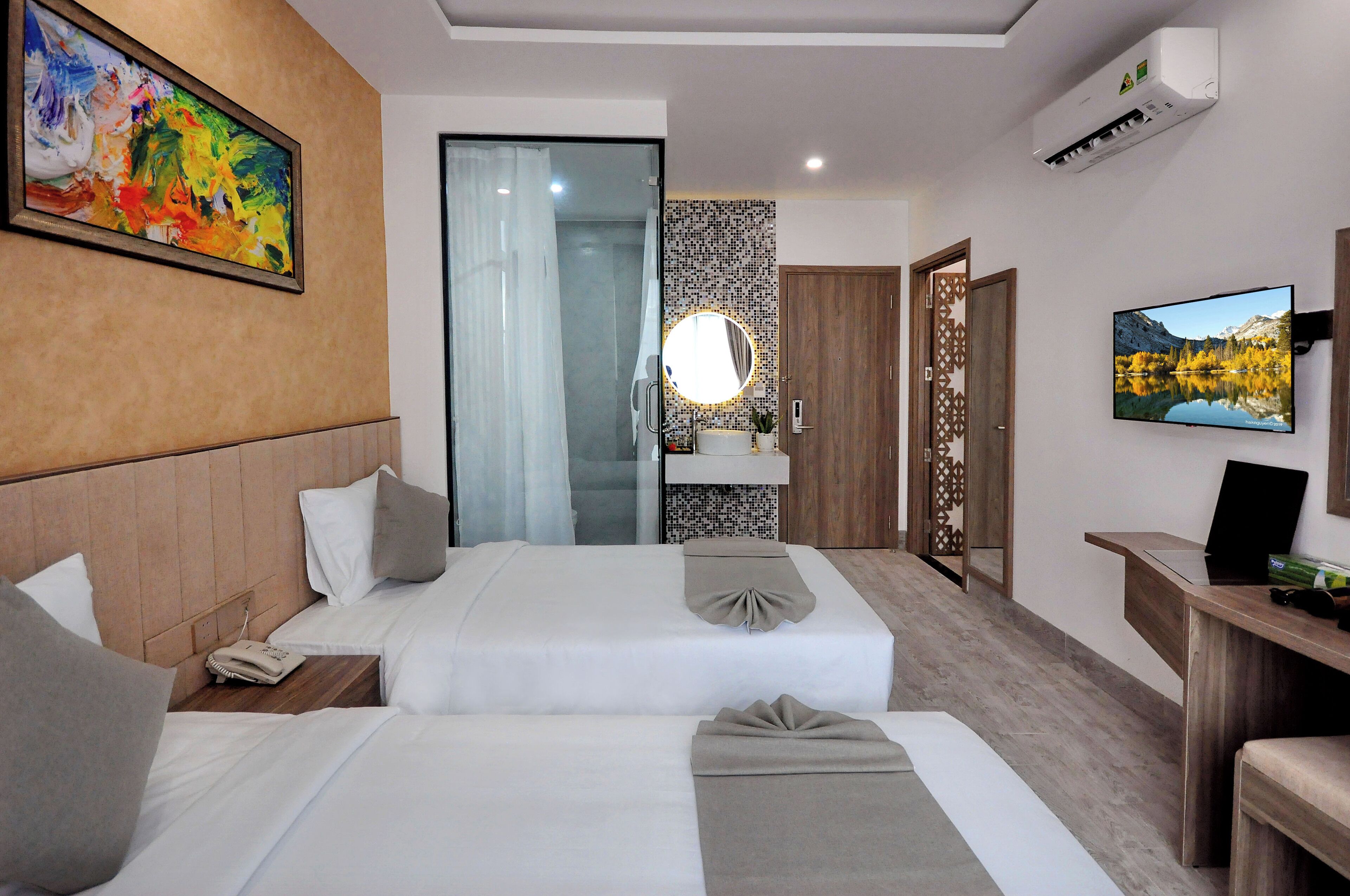 Een hotelkamer met twee bedden, een grote spiegel, een televisie en een schilderij aan de muur.