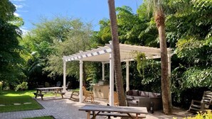 Un espacio al aire libre con techo, una pérgola, bancos de madera y una mesa de picnic.