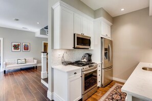 A modern kitchen with white cabinetry, stainless steel appliances, and a marble countertop. - Buttercup - 3BR Home Close to the Convention Center + Walk to Downtown (West Palm Beach)