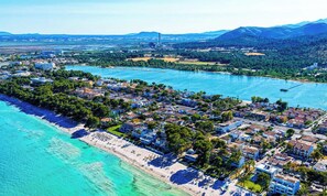 Luftaufnahme einer Küstenstadt mit Strand, Wohnhäusern und einer großen Wasserfläche.