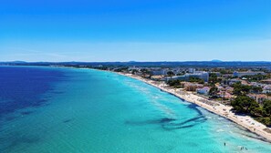 Eine Küstenstadt mit Strand, Gebäuden und klarem, blauem Wasser.