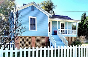 A two-story house with a porch, a white picket fence, and a brick foundation. - Immaculate Cottage in the Historic District. Quiet street, large fenced yard. (Washington)