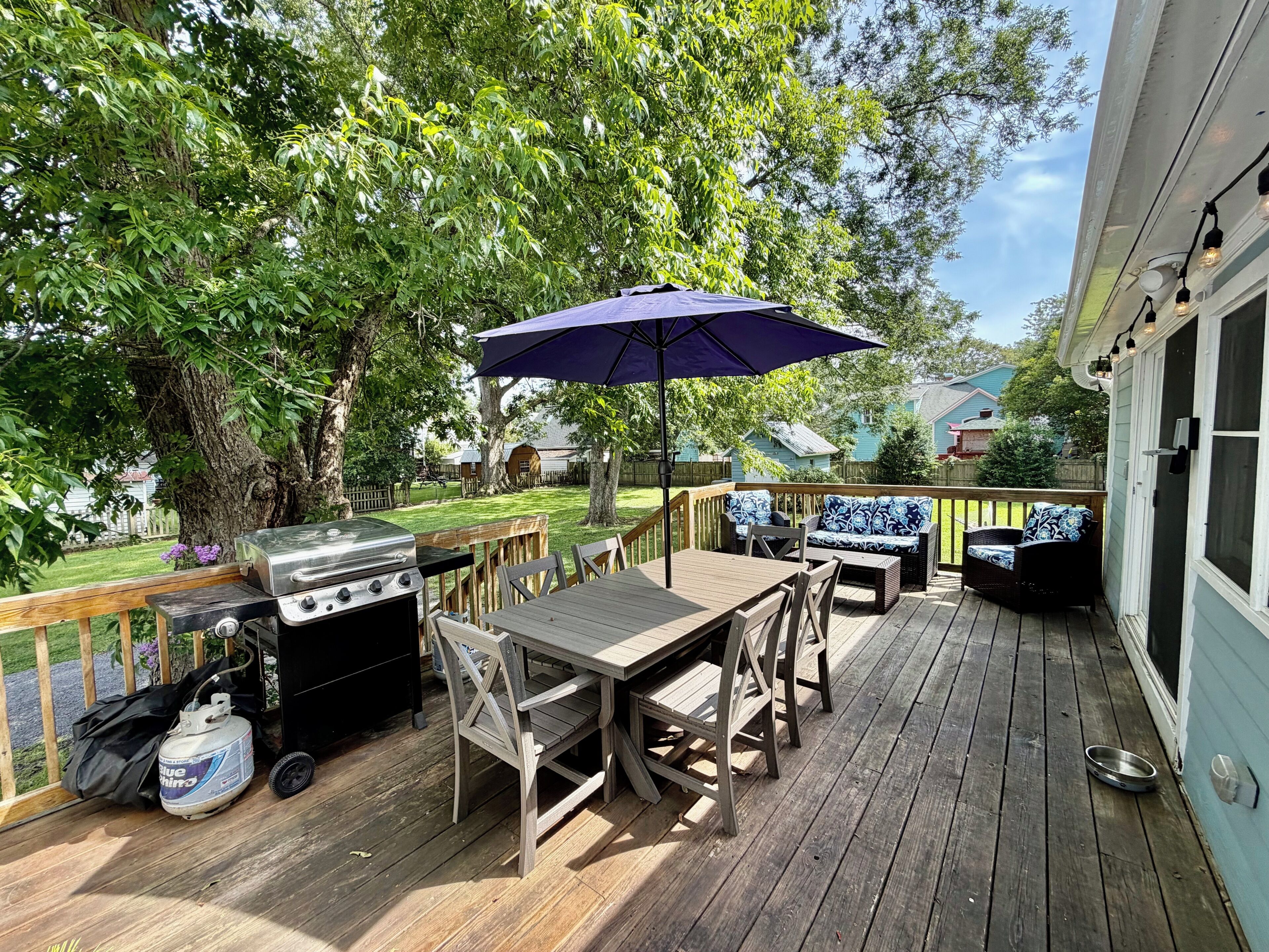 A wooden deck with a grill, outdoor furniture, and a large umbrella.