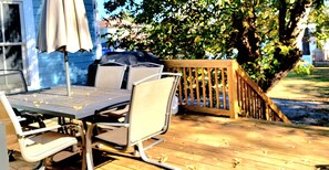 An outdoor dining area with a table and chairs, a grill, and a wooden deck. - Immaculate Cottage in the Historic District. Quiet street, large fenced yard. (Washington)