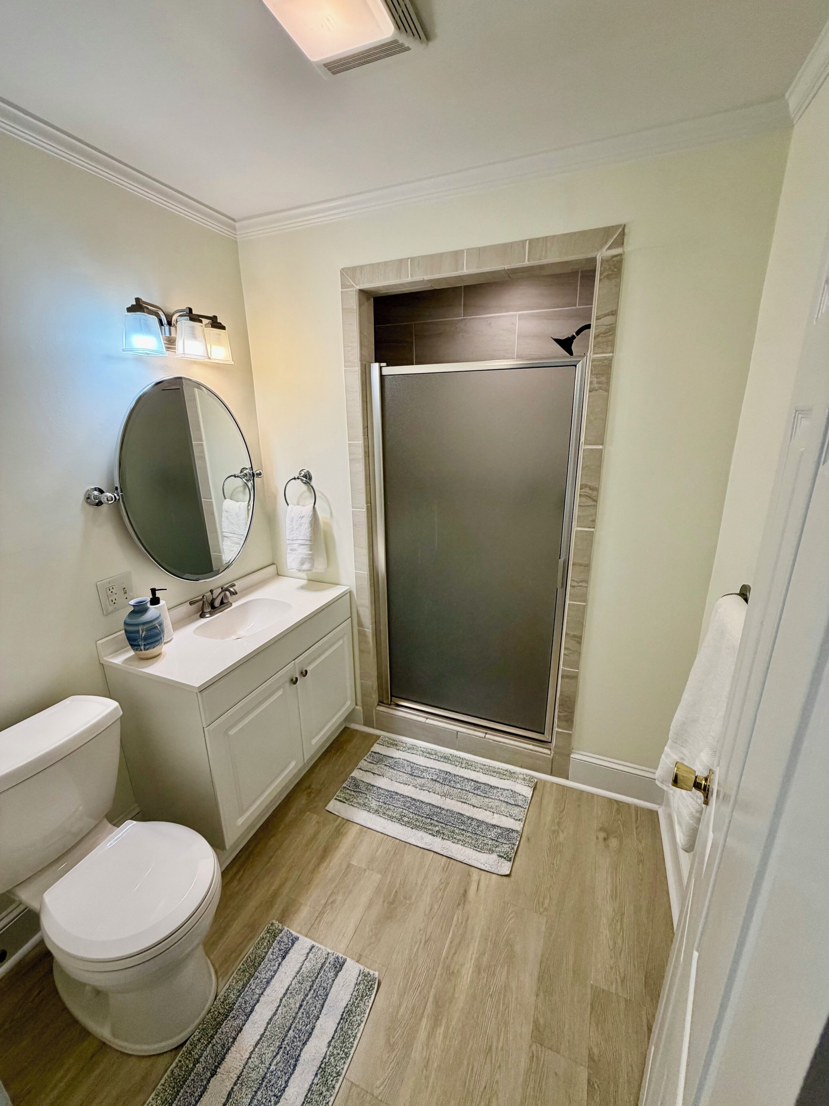 A bathroom with a toilet, sink, mirror, and shower.