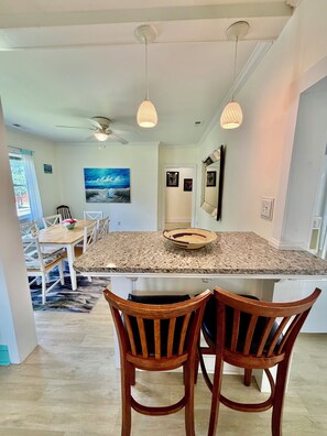 A modern kitchen with a granite countertop, two wooden chairs, pendant lights, and a ceiling fan. - A Beautifully Kept Historic Retreat, Walking Distance to Downtown (Washington)