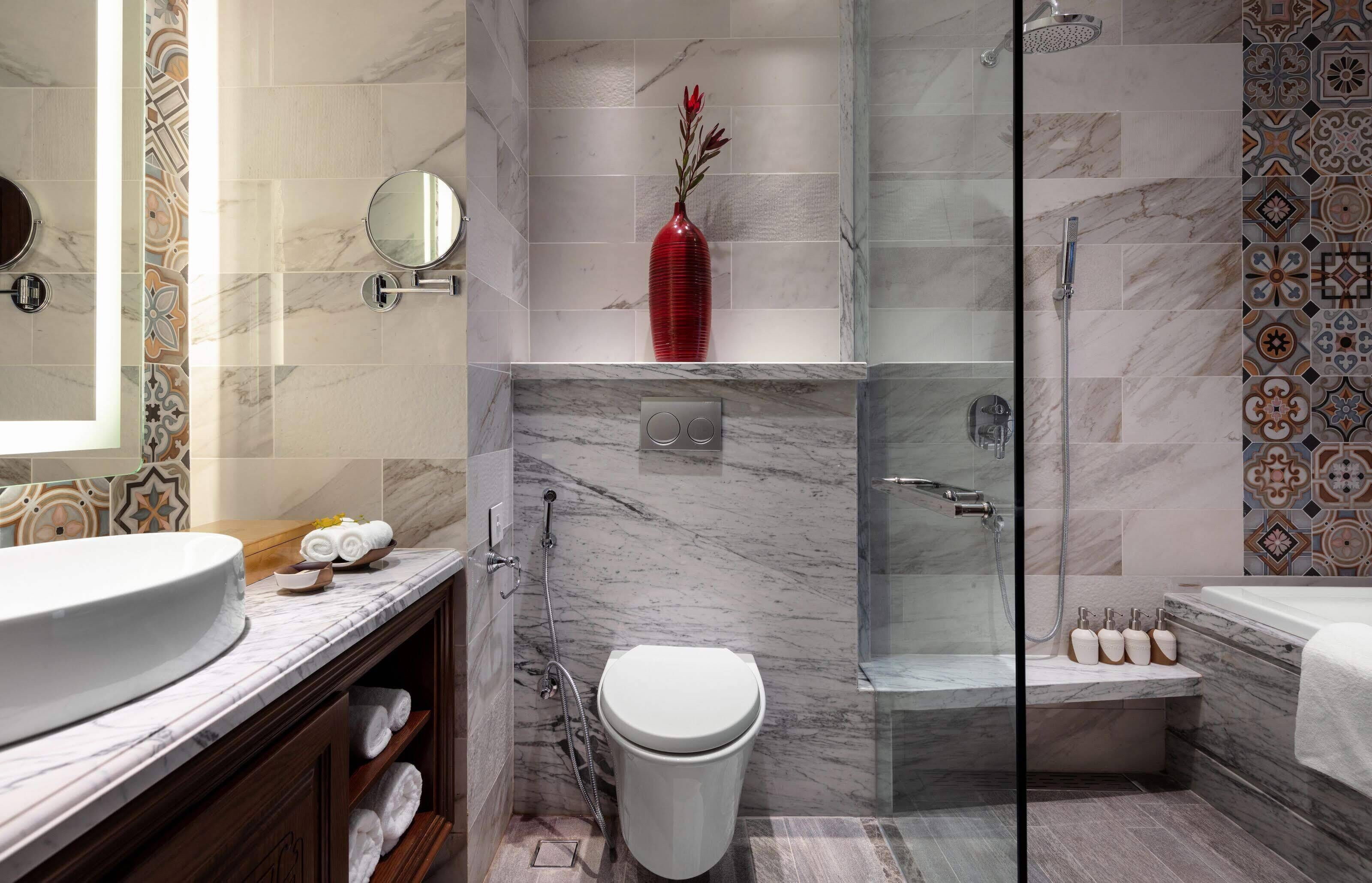A modern bathroom with a marble sink, a toilet, a shower, and a bathtub.