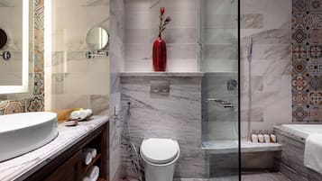 A modern bathroom with a marble sink, a toilet, a shower, and a bathtub.