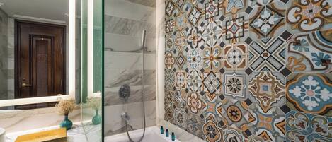 A bathroom with a shower, a marble sink, and a tiled wall with a geometric pattern.