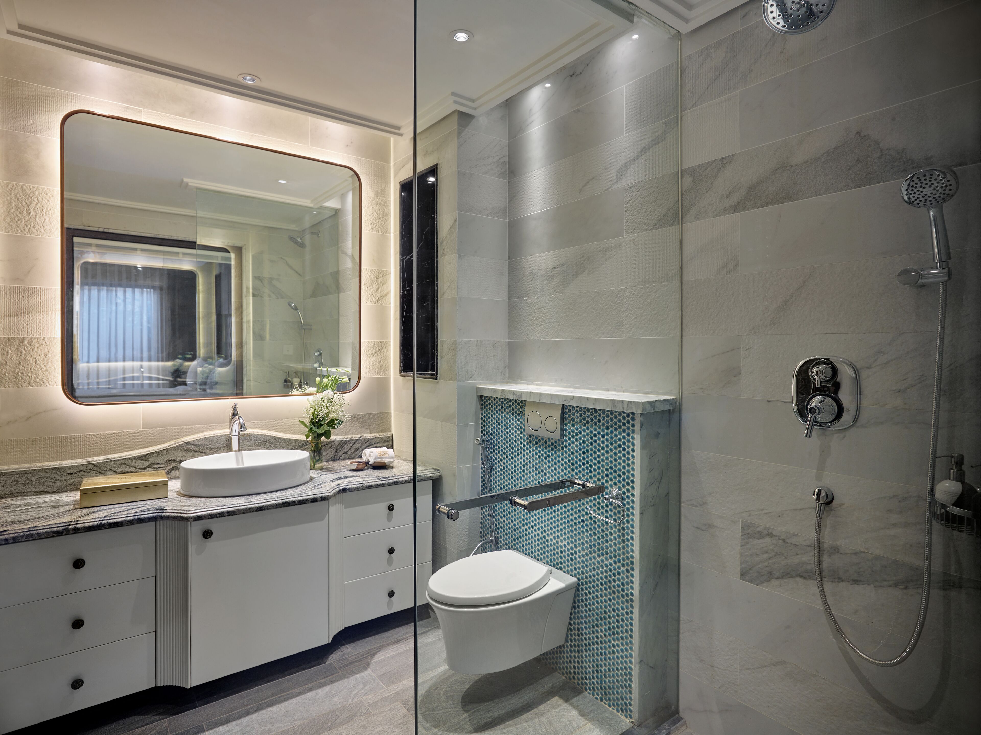Une salle de bain moderne avec un grand miroir, un lavabo et une douche.