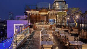 Um bar no terraço com área externa, balcão e estrutura de vidro com uma árvore.