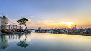 Piscina no terraço com uma árvore, horizonte urbano e edifícios ao fundo.