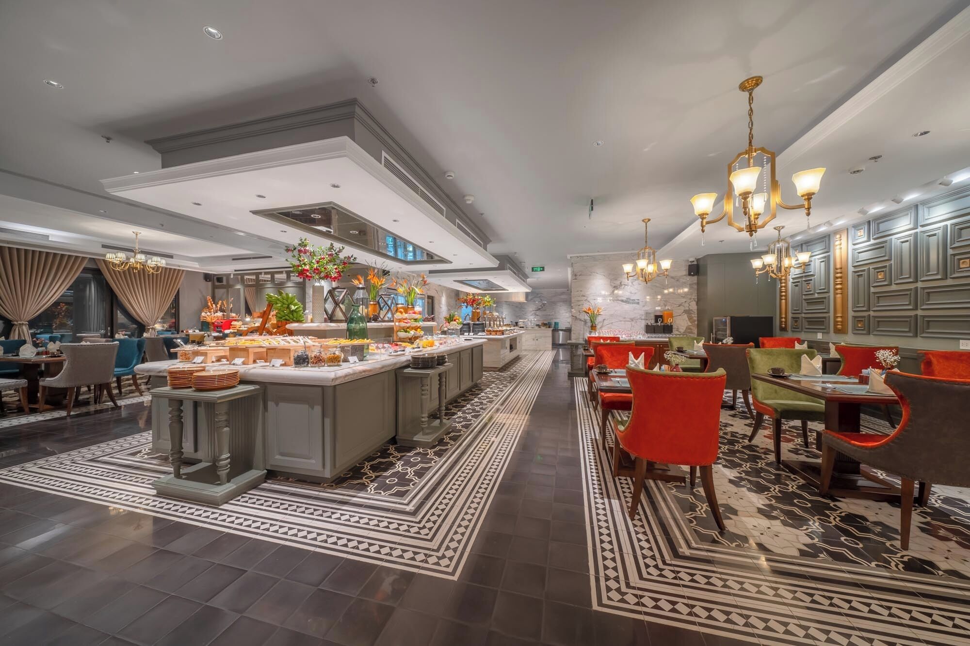 Un hall d’hôtel moderne doté d’un espace buffet, de différents types de sièges et d’un éclairage décoratif.