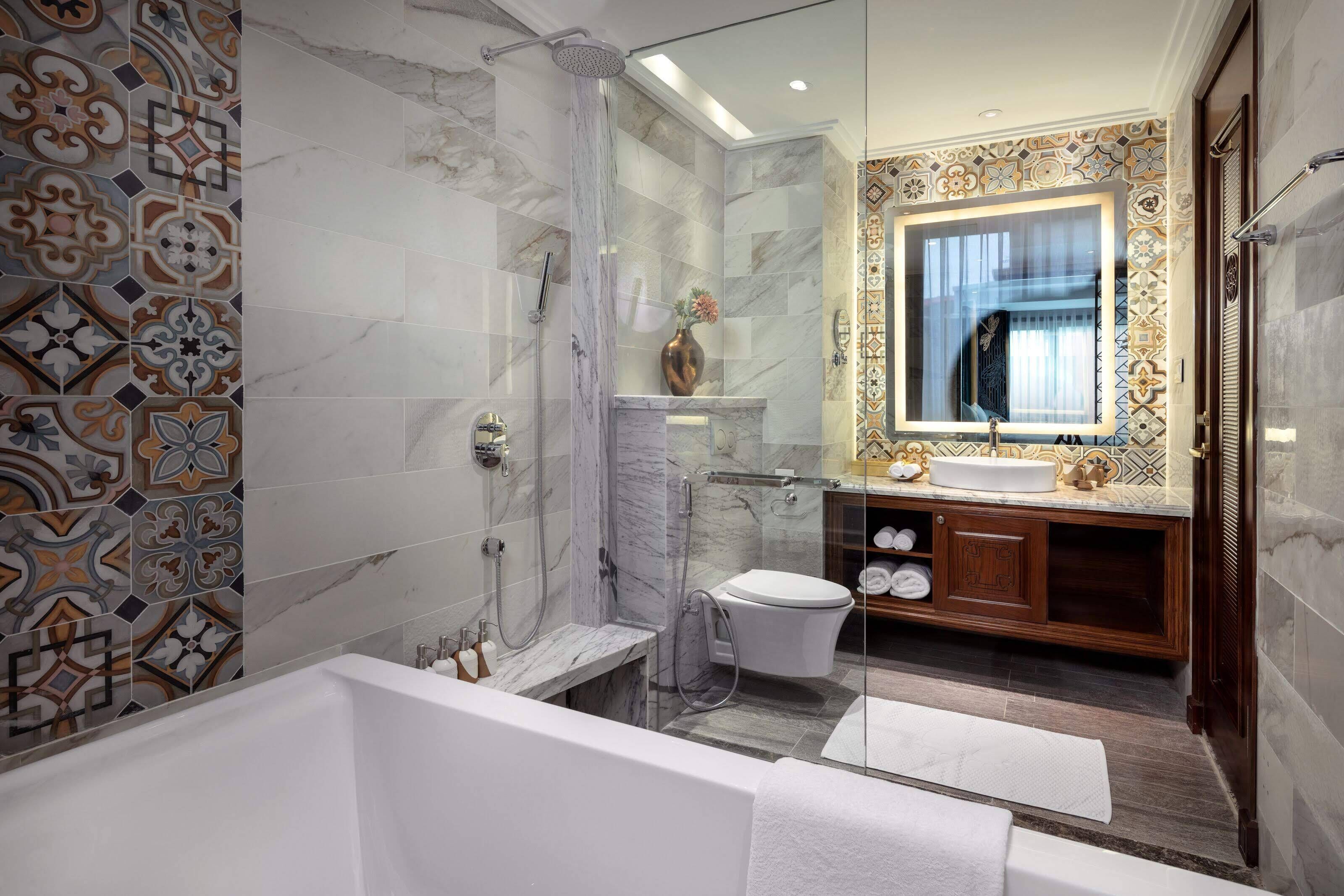 A modern bathroom with a marble shower, a vanity with a sink, and a large mirror.