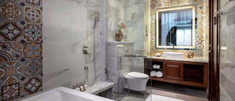 A modern bathroom with a marble shower, a vanity with a sink, and a large mirror.