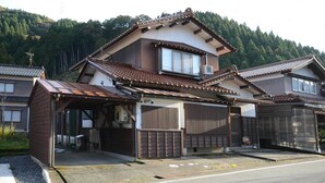 A two-story house with a sloped roof, a garage, and a covered porch. - Guest House IROHA Lotusland (Kaga)