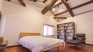 A bedroom with a wooden bed, a bookshelf, a desk, and a window with blinds. - Guest House IROHA Lotusland (Kaga)