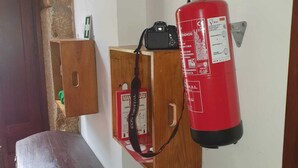 Un extintor colgado en una pared de una habitación con un banco de madera y un muro de piedra.
