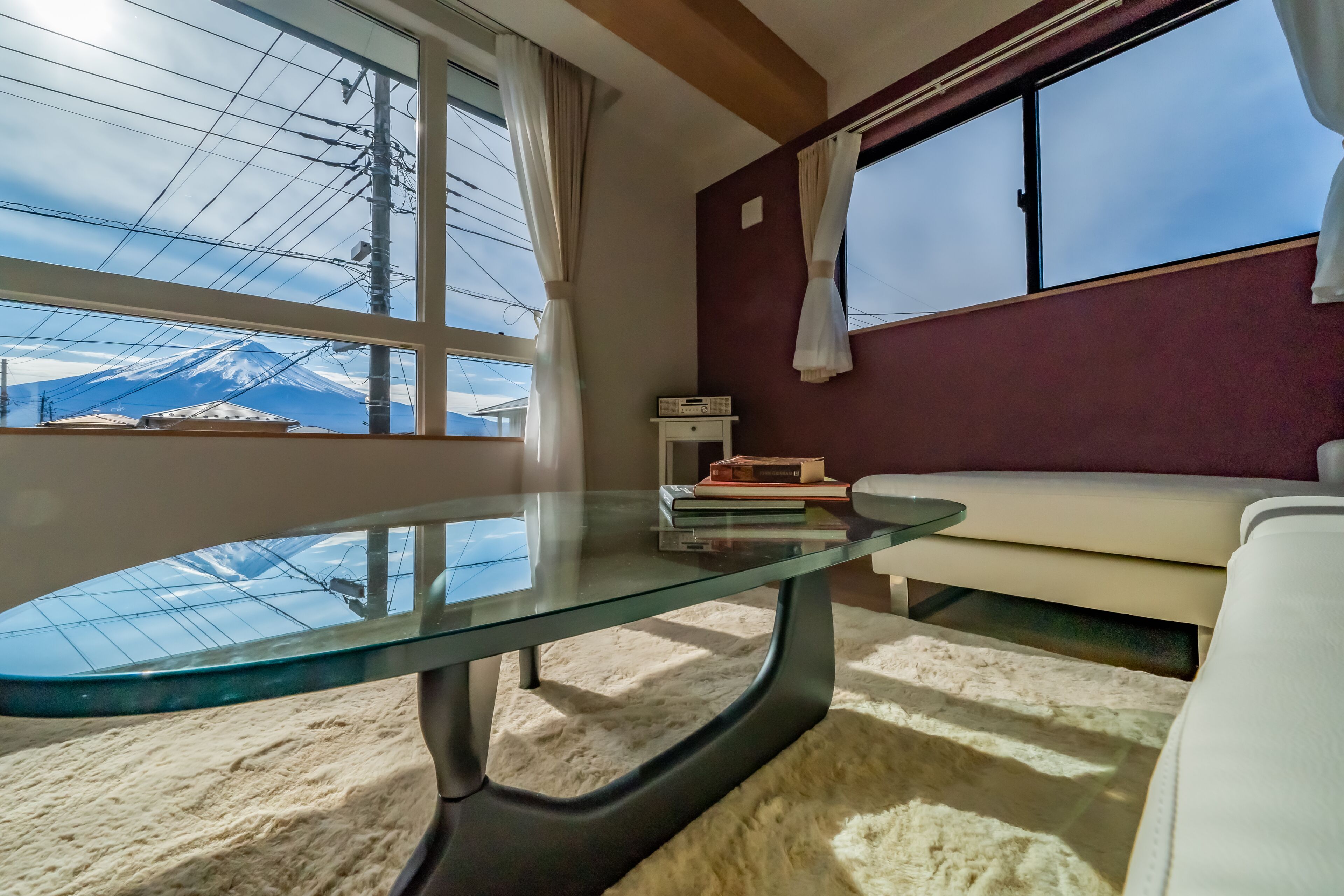 Een kamer met een glazen tafel, een bank en uitzicht op een berg.