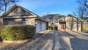 A two-story house with a brick exterior, two garage doors, and a driveway leading to the front entrance.
