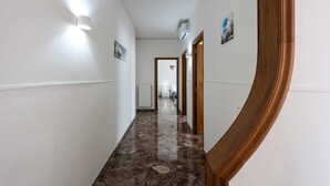 Un pasillo con paredes blancas, suelo de mármol y marco de puerta de madera.
