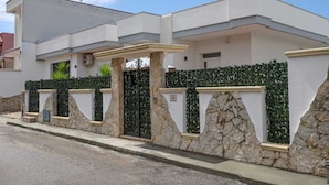 Una casa moderna de dos pisos con fachada de piedra, un portón de metal y un césped cuidado.