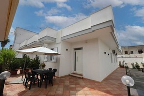 A modern building with a patio area featuring a table and chairs, surrounded by potted plants. - Holiday house "grandfather flower" (Leverano)