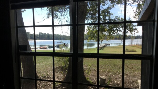 Ein Fenster mit Blick auf einen See, eine Anlegestelle und Bäume.