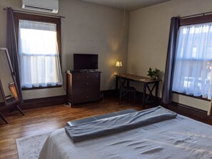 Een hotelkamer met een bed, bureau, dressoir, televisie en een raam met gordijnen.