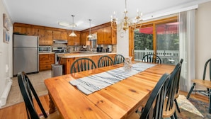 Une cuisine moderne avec des meubles en bois, un îlot central et un coin repas comprenant une table et des chaises en bois.