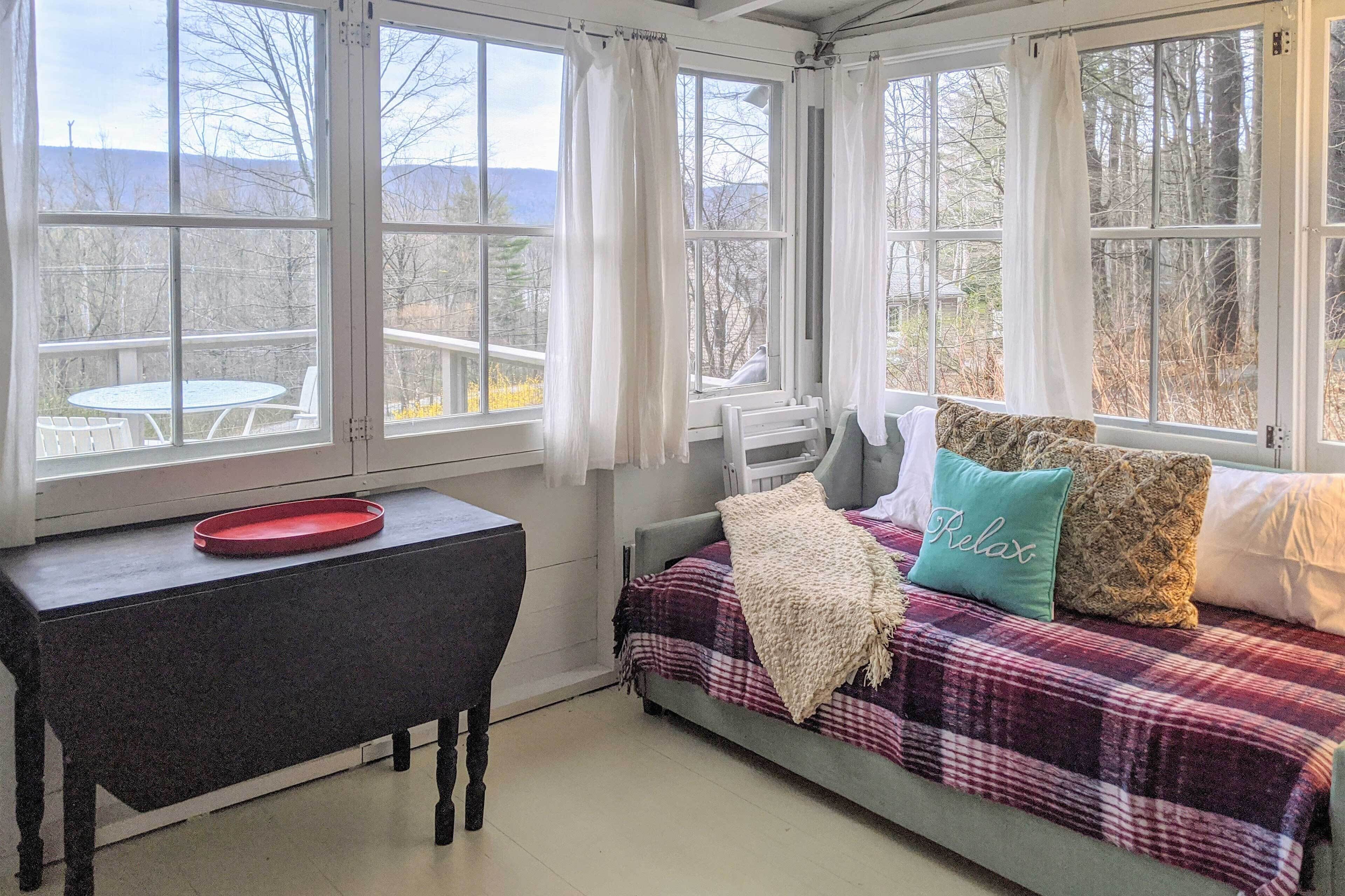 Una habitación acogedora con una cama, una mesita y vistas a una terraza y montañas.