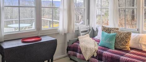 Una habitación acogedora con una cama, una mesita y vistas a una terraza y montañas.