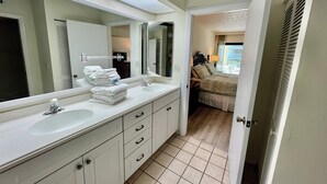 Casa de banho de hotel com duas pias, um espelho grande e um closet espaçoso.