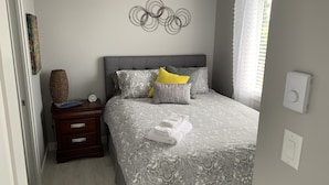 A bedroom with a grey patterned bedspread, a grey headboard, and a wall art piece. - LOCATION LOCATION LOCATION! IMMACULATE 1 BEDROOM SUITE-ULTRA PRIVATE AND UNIQUE! (Victoria)