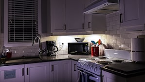 A kitchen with white cabinets, a stove, a microwave, and a coffee maker. - LOCATION LOCATION LOCATION! IMMACULATE 1 BEDROOM SUITE-ULTRA PRIVATE AND UNIQUE! (Victoria)