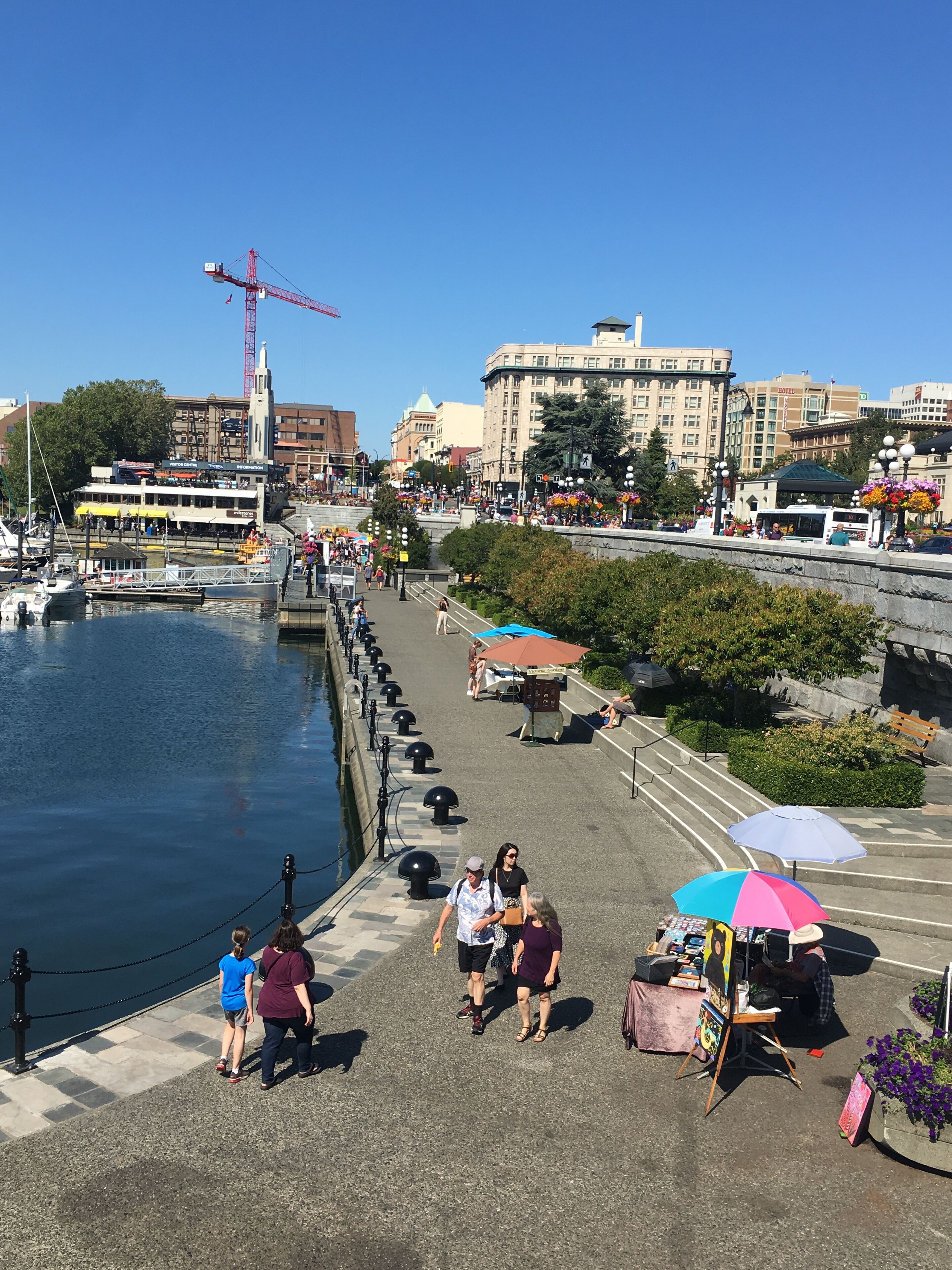 A waterfront promenade with a dock, a pedestrian walkway, and a row of shops.