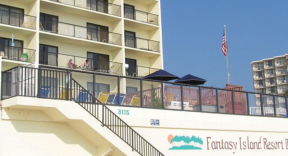 A multi-story building with balconies, a flag, and a sign for Fantasy Island Resort.