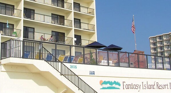 Un edificio de varios pisos con balcones, una bandera y un letrero que indica Fantasy Island Resort.