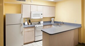 Una cocina compacta equipada con refrigerador, microondas, estufa y lavamanos.