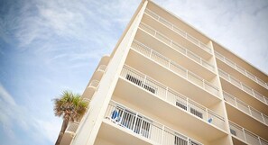 Un hotel de varios pisos con balcones y una palmera.