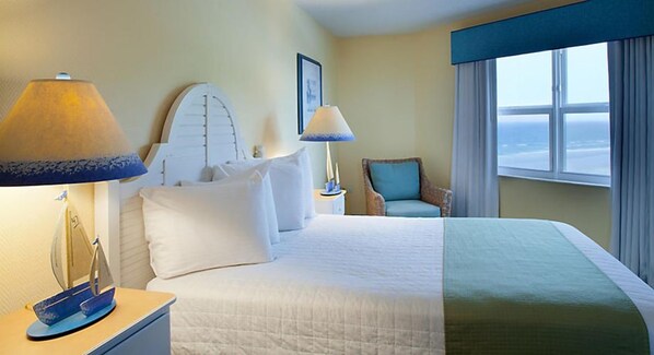 Habitación de hotel con cama, dos lámparas de noche, una silla y ventana con vistas.