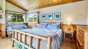 A wooden-framed bedroom with a bed, bedside tables, and a window. - Deer Harbor Cottage on the Bluff (Eastsound)